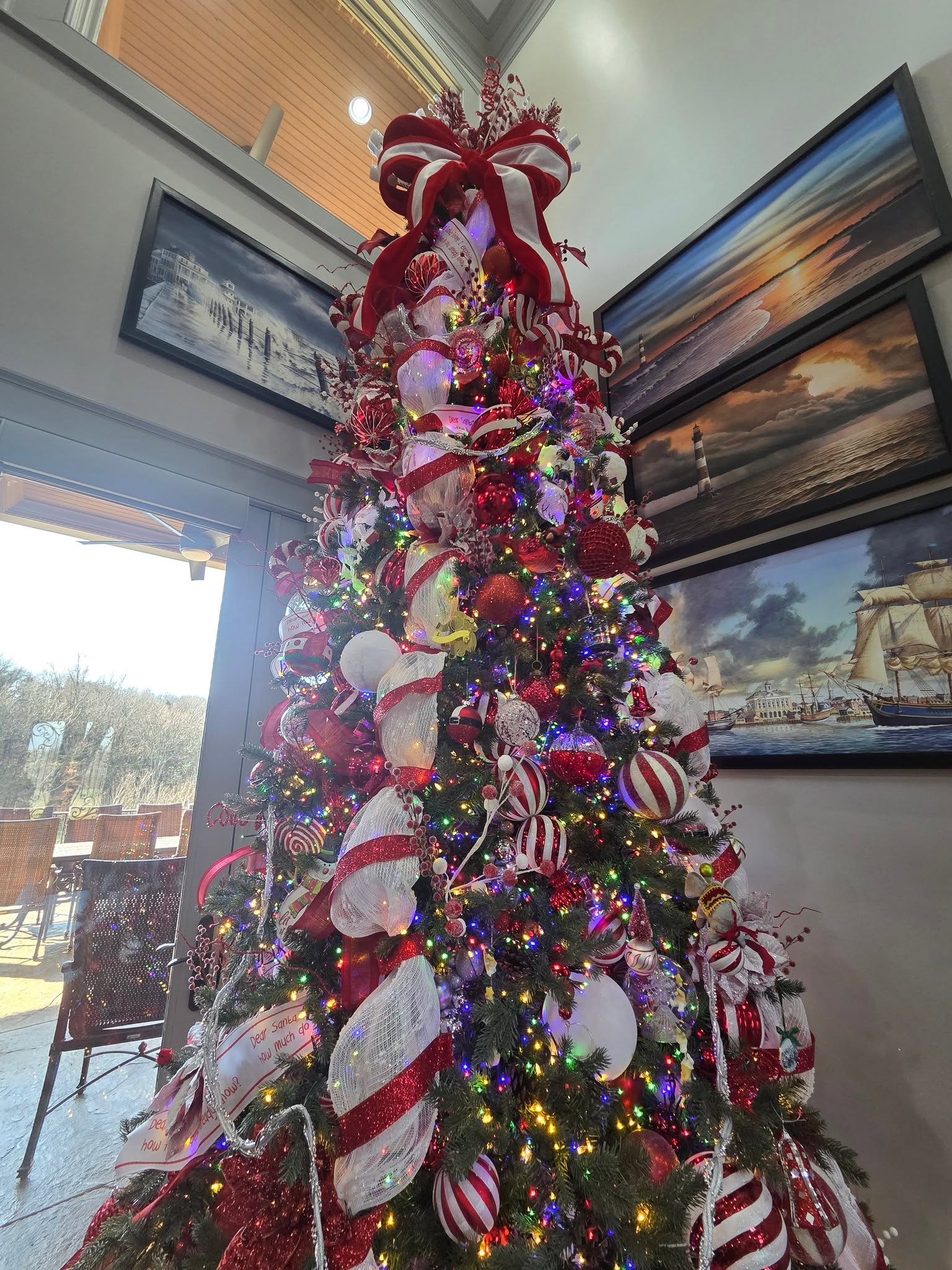 A tall red and white themed Christmas tree in a two-storey living room